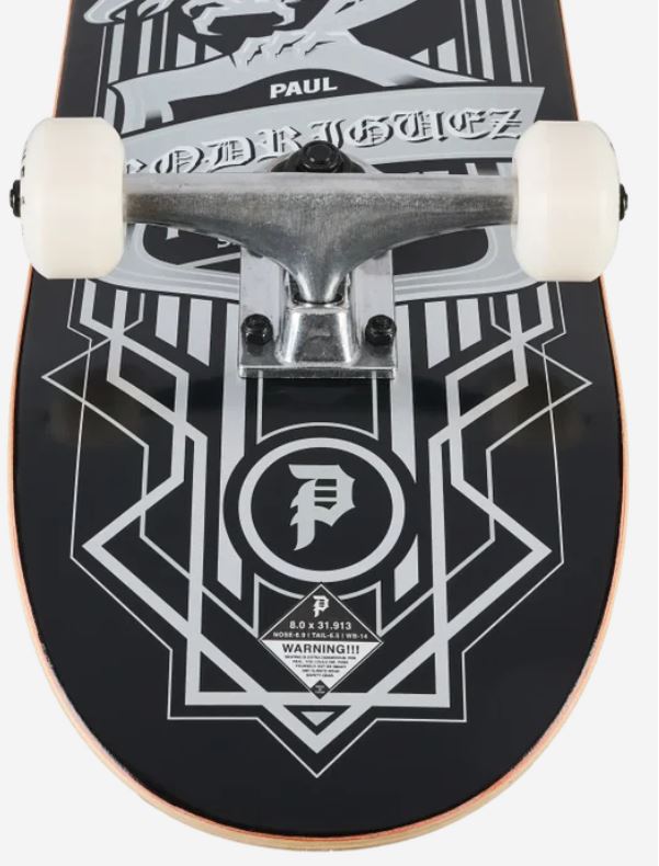 Close-up of a skateboard deck underside with a black base, white geometric graphic lines, a white circular logo with a stylized P, and a silver truck with white wheels. The graphic includes the text 'PAUL' and 'DEBtorGUYEZ'.